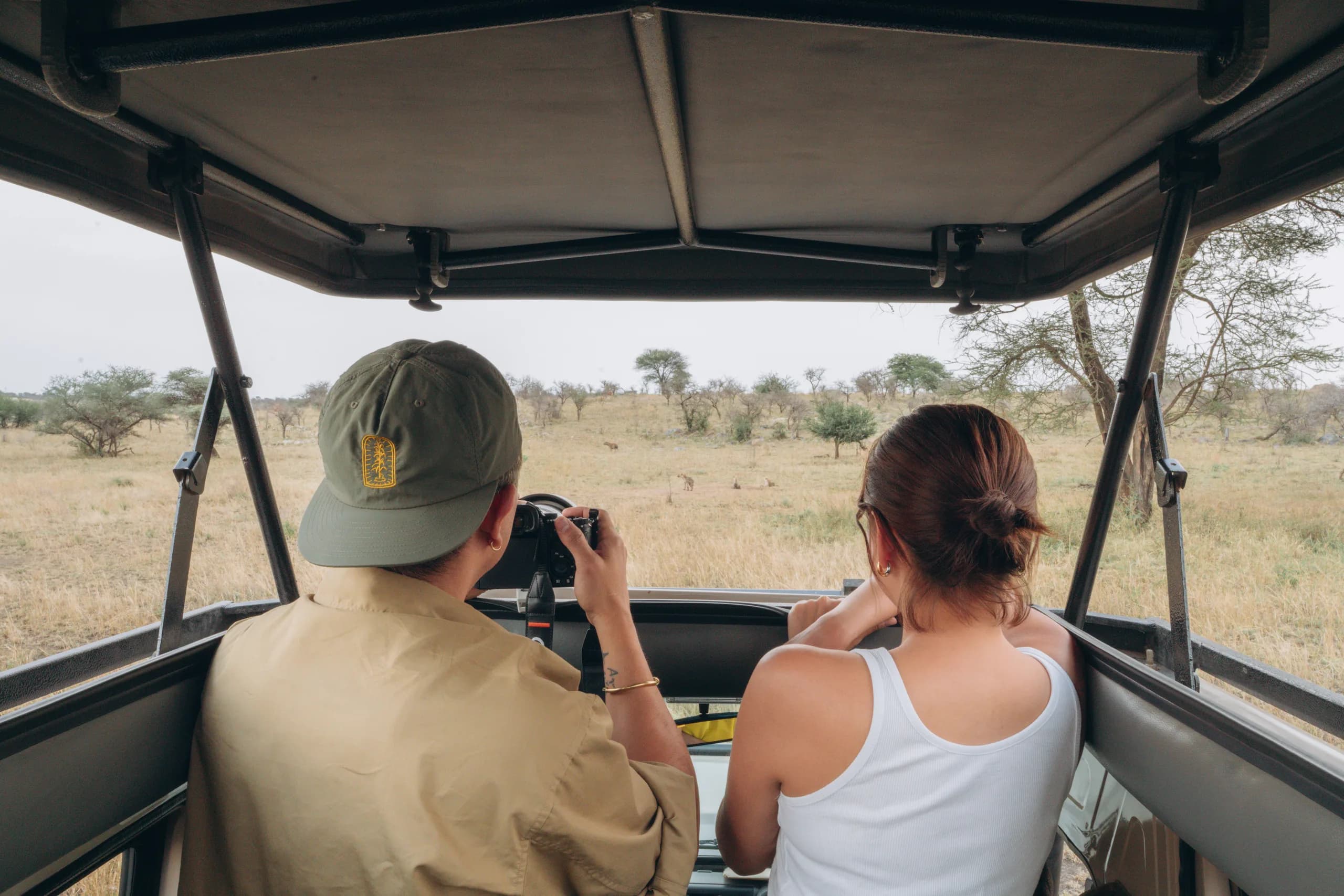 Guide and guest in an open-sided safari vehicle during a game drive